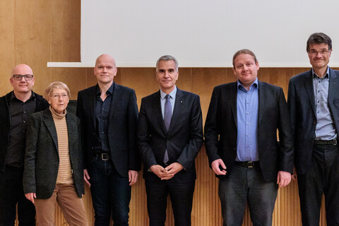 Gruppenfoto zum Tag der Philosophie am 21.11.2024. Von links nach rechts stehen nebeneinander: Prof. Dr. Wolfgang Freitag, Prof. Dr. Dr. h. c. Ursula Wolf, Prof. Dr. Dietmar Heidemann, Prof. Dr. Thomas Fetzer, Prof. Dr. Andreas Cassee, Prof. Dr. Bernward Gesang. Im Hintergrund holzvertäfelte Bühne bei herabgelassener Leinwand der Aula der Universität Mannheim.