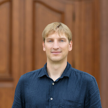 PD Dr. Marc Andree Weber. Er trägt ein dunkelblaues Jeanshemd und steht im Ehrenhof des Mannheimer Schlosses.